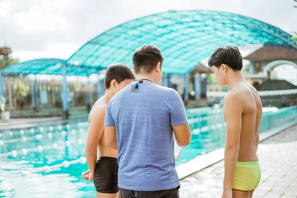 Z tyłu strzał trenera i nastolatek pływak w kąpielówki briefing — Zdjęcie stockowe