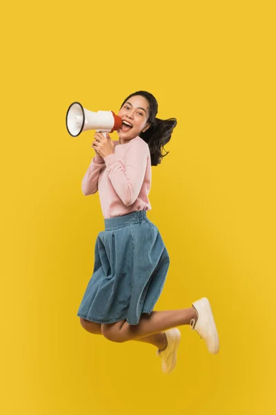 A girl jumping and screaming using a megaphone on — Stock Photo, Image