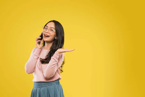 Mooie aziatische vrouw in bril glimlachen terwijl bellen met behulp van een mobiele telefoon — Stockfoto
