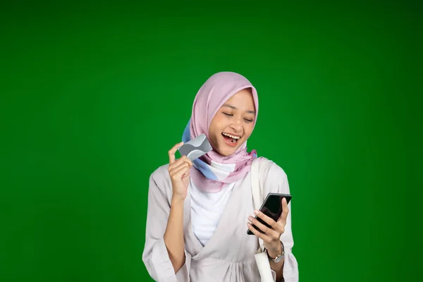 Femme excitée dans hijab en utilisant un téléphone mobile tout en tenant la carte ATM — Photo