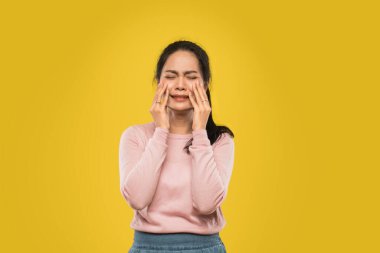 Acı içinde ağlarken iki yanağını tutan Asyalı kadın.