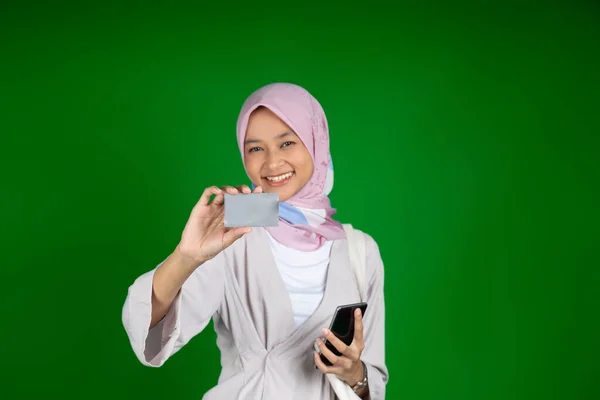 Emocionada mujer musulmana asiática mientras usa un teléfono móvil y una tarjeta de crédito —  Fotos de Stock