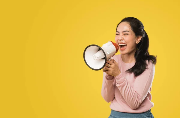 Asian woman screaming while holding megaphone with two hands making announcement — Stock Photo, Image