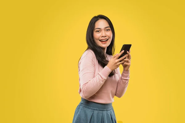 Attraktiv kvinna med löst hår ler samtidigt skriva meddelande med mobiltelefon — Stockfoto