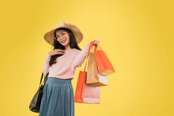 Vacker kvinna i hatt och glasögon ler med handen bär shopping papperspåse — Stockfoto