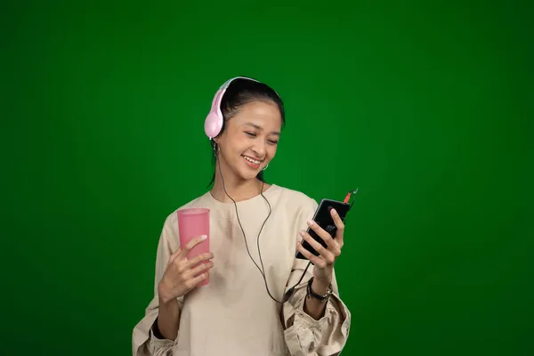 Niña usando auriculares mientras bebe mientras escucha música — Foto de Stock