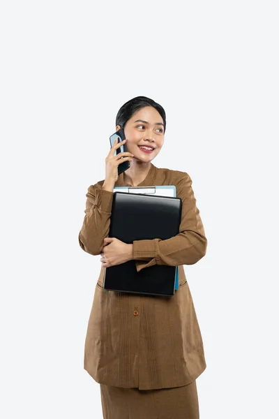 Profesora de uniforme hace una llamada usando el teléfono mientras lleva el portátil —  Fotos de Stock