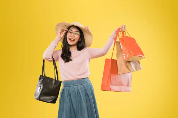 Asiatisk kvinna i hatt och glasögon ler med handen bär shoppingväska — Stockfoto