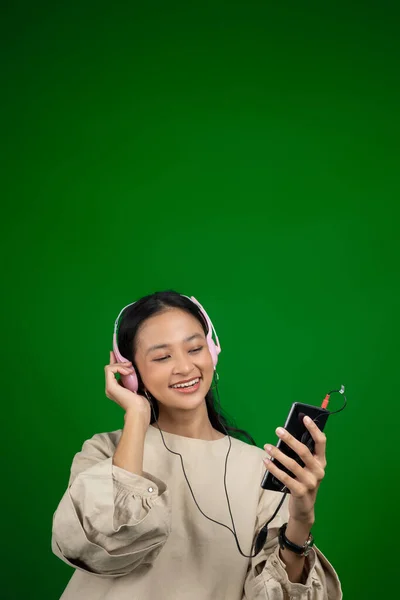 Menina usando fones de ouvido e segurando um telefone celular enquanto ouve música — Fotografia de Stock