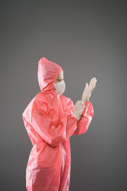 PPE 'de duran bir sağlık çalışanı ve eldiven takarken maske.
