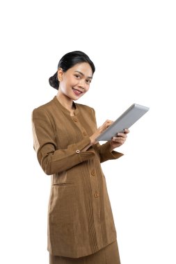 Endonezyalı kadın devlet memuru üniforması giymiş, tablet kullanırken başparmağı yukarıda.