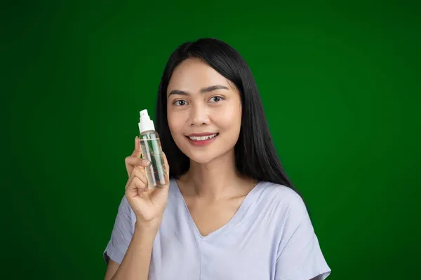 Beautiful woman with long hair holding bottle of serum spray after make up — Stock Photo, Image