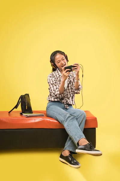 Auriculares de niña jugando juego con un teléfono móvil — Foto de Stock