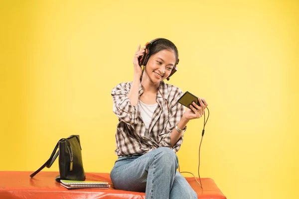 Dívka sluchátka hrát hru pomocí mobilního telefonu — Stock fotografie