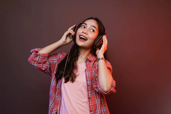 Χαρούμενο κορίτσι απολαμβάνοντας τη μουσική χρησιμοποιώντας ακουστικά με δύο χέρια κρατώντας ακουστικά — Φωτογραφία Αρχείου