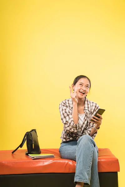 Mädchen lächelt mit Geste Ideen zu finden, während Blick auf Handy-Bildschirm — Stockfoto