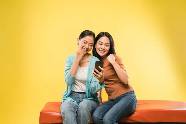 携帯電話の画面を見ると手で幸せそうな2人の若い女性が — ストック写真