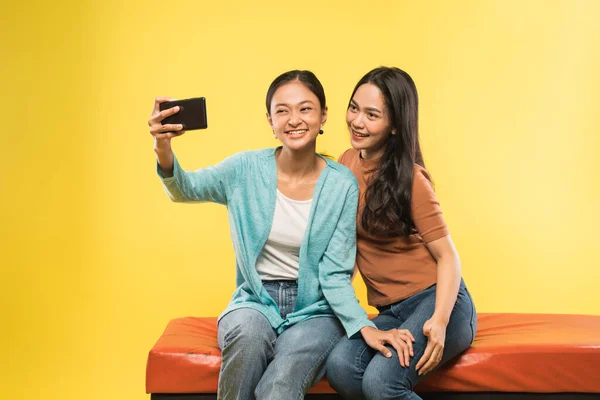 美しいアジア系の女性が携帯電話のカメラを使って — ストック写真