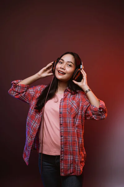 Veselá dívka těší hudbu pomocí sluchátek se dvěma rukama drží sluchátka — Stock fotografie