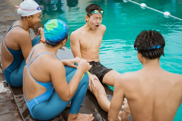 L'expression douloureuse d'un adolescent aux jambes serrées assis au bord de la piscine — Photo