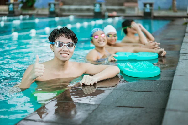 Ένα χαμογελαστό έφηβο αγόρι με τους αντίχειρες σηκωμένους ενώ στεκόταν σε μια πισίνα — Φωτογραφία Αρχείου