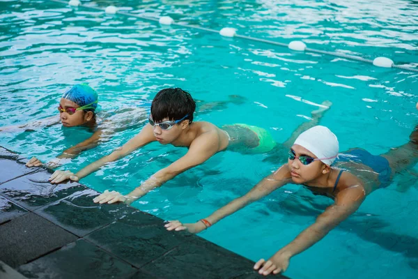 Close up of two teenage girls and a boy with swimming goggles doing a float — Stock Photo, Image