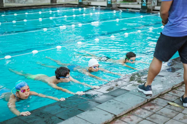 Fille et garçon faisant de l'exercice de natation à la piscine — Photo