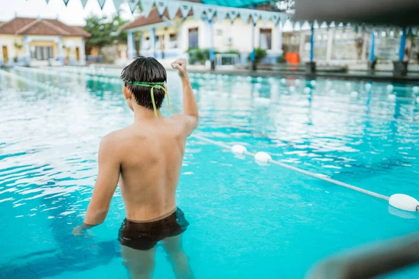 Shot from behind of male athlete with clenched fist in pool after entering the finish line — Stock Photo, Image