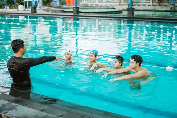 Инструктор в бассейне указывая во время лекции четырех подростков — стоковое фото