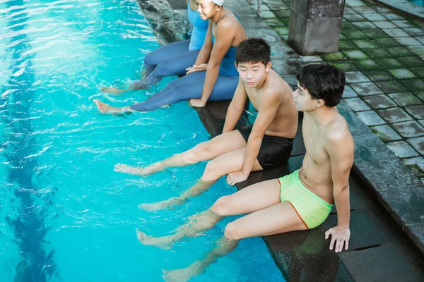 两个穿着泳裤坐在游泳池边的年轻人 — 图库照片