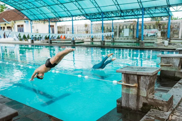 男子运动员和女子运动员在发信号后跳入游泳池 — 图库照片