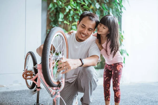 Padre fissaggio ruote bicicletta con sua figlia — Foto Stock