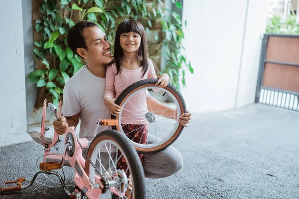 Padre e hija sonriendo mientras llevan una rueda —  Fotos de Stock