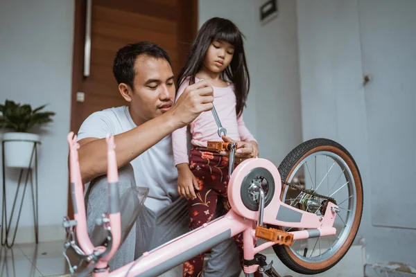 Baba kızına bisiklet pedalı takıyor. — Stok fotoğraf