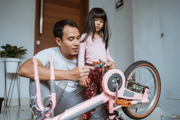 Azjatycki ojciec dokręca pedał roweru z córką — Zdjęcie stockowe