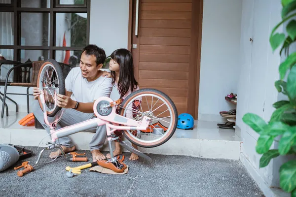 Asijský otec sedí při opravě kolo pneumatiky se svou dcerou — Stock fotografie