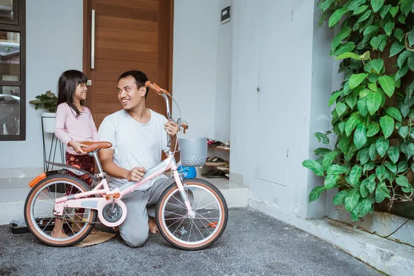 Filha conversando com seu pai depois de terminar de montar sua bicicleta — Fotografia de Stock