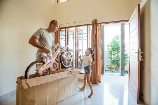 Daughter dances happily when her father unboxes a mini bike — Stock Photo, Image