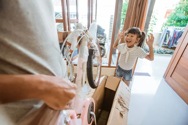 Дочь удивлена и счастлива, когда распаковывает мини-байк — стоковое фото