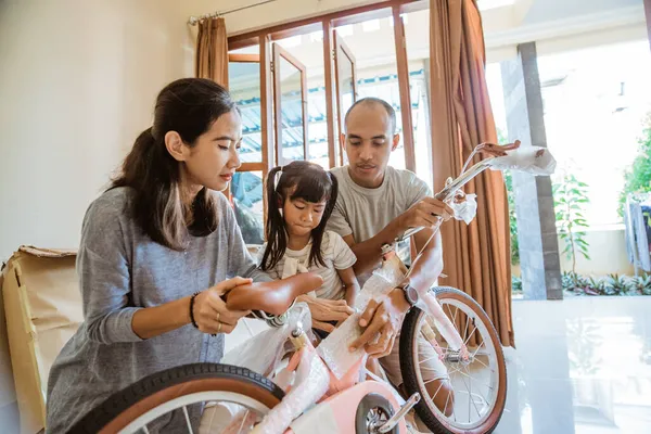 Vater, Mutter und Tochter beim Auspacken eines neuen Mini-Bikes — Stockfoto