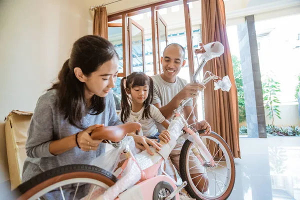 Glücklicher Vater, Mutter und Tochter packen gemeinsam neues Mini-Fahrrad aus — Stockfoto