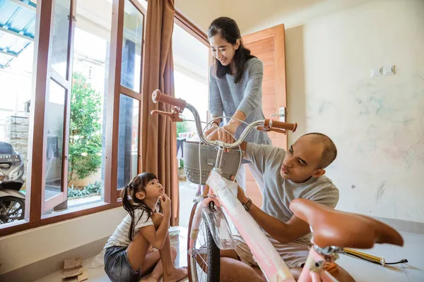 Padre, madre e hija instalando cesta en la nueva mini bicicleta —  Fotos de Stock