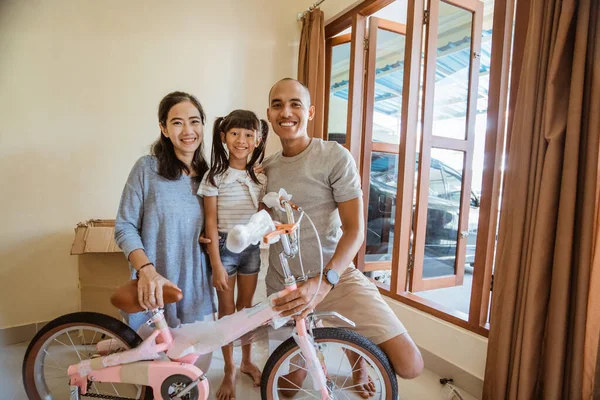 Smiling Asian father, mother and daughter holding new mini bike — Stock Photo, Image