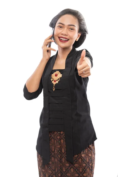 Frau in Kebaya zeigt beim Telefonieren Daumen nach oben — Stockfoto