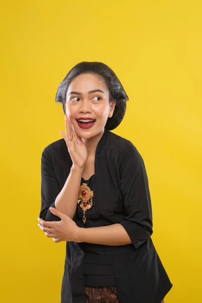 Kvinna bär traditionell kebaya klänning öppen mun talar med händerna bredvid läppar — Stockfoto