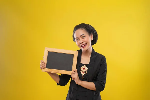 Asiatico donna wearing kebaya smiling mentre holding piccolo nero lavagna — Foto Stock