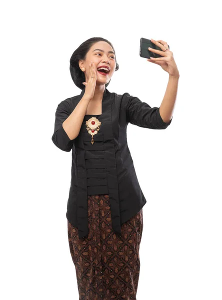 Mujer usando vestido de Kebaya haciendo una videollamada usando un teléfono inteligente — Foto de Stock
