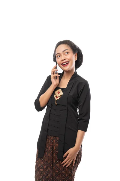 Mulher javanesa com vestido tradicional Kebaya pensamento gesto segurando smartphone — Fotografia de Stock