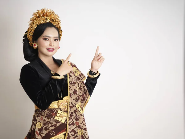 Smiling balinese woman wearing traditional clothes with finger pointing — Stock Photo, Image