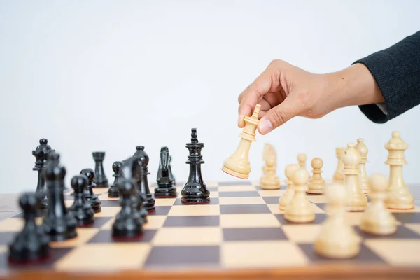 Mano che tiene il re per attaccare mentre gioca a scacchi sulla scacchiera — Foto Stock